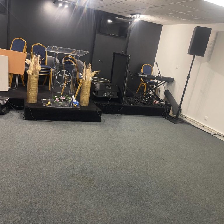 Scène de performance avec instruments de musique et chaises, dans une salle sobre.